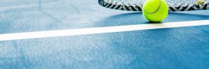racket and padel ball on blue court. horizontal photo