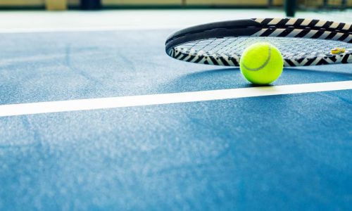 racket and padel ball on blue court. horizontal photo