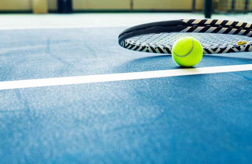 racket and padel ball on blue court. horizontal photo